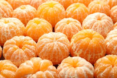 Arka plan olarak birçok olgun soyulmuş mandalina, yakın plan