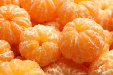 Arka plan olarak birçok olgun soyulmuş mandalina, yakın plan