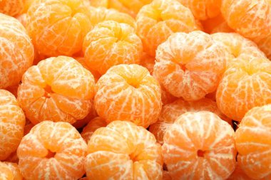 Arka plan olarak birçok olgun soyulmuş mandalina, yakın plan