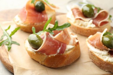 Krem peynirli nefis bruschettalar, prosciutto, yeşil zeytin ve roka masada, yakın plan.