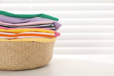 Çamaşır sepetinde, pencerenin yanındaki beyaz masada giysiler, yakın çekim. Metin için boşluk