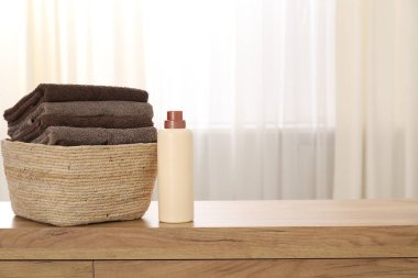 İçerideki ahşap dolapta havlular ve bir şişe deterjan olan çamaşır sepeti, mesaj için yer.