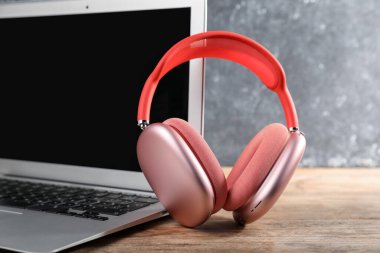 Kaliteli kulaklıklar ve dizüstü bilgisayarlar ahşap masada, yakın plan.