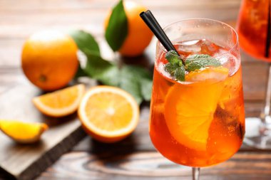 Bir bardak serinletici spritzer kokteyli ve portakallar ahşap masada, yakın plan.