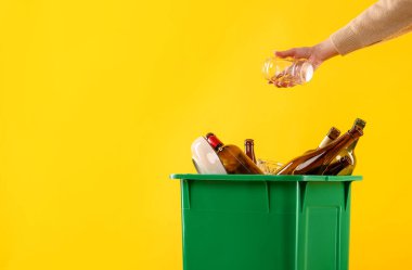 Turuncu arka planda çöp kutusuna çöp atan bir kadın. Mesaj için yer var. Atık sıralama