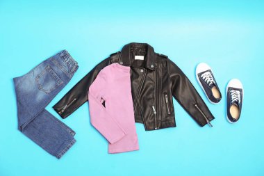 Açık mavi arka planda şık çocuk kıyafetleri ve ayakkabıları olan düz bir kompozisyon.