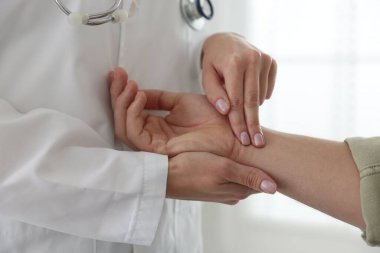 Doktor klinikte adamın nabzını kontrol ediyor.