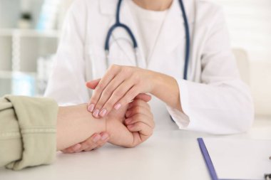 Doktor masadaki parmaklarıyla adamın nabzını kontrol ediyor.