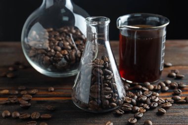 Kahve, fasulye ve beher dolu cam mataralar siyah arka planda, yakın plan.