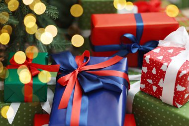 Kapalı alanda Noel ağacının altında bir sürü hediye kutusu var.