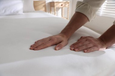 Yatakta yumuşak yatağa dokunan adam, yakın plan.