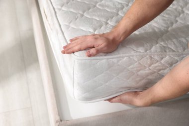 Yatakta yumuşak yatağa dokunan adam, yakın plan.