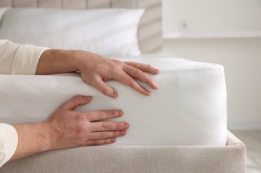 Adam yatak çarşaflarını kapalı bir yere koyuyor.