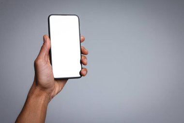 Açık gri arka planda boş ekranlı akıllı telefon tutan adam, yakın plan. Tasarım için model