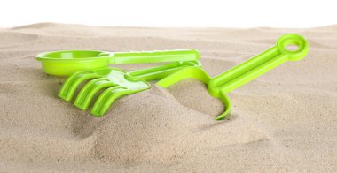 Çocuklar için plaj oyuncakları ve beyaz pankartta izole edilmiş kum. Plastik elek, tırmık ve kürek.