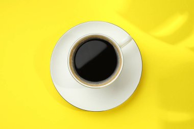 Sarı masada fincanda Aromatik kahve, üst manzara.