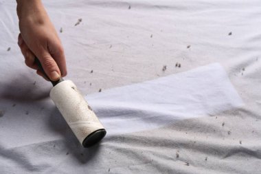 Beyaz kumaş üzerinde pamuk rulo kullanan kadın, yakın plan.