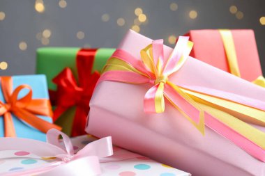 Gri arka planda güzel paketlenmiş hediyeler, bulanık ışıklar, yakın plan. Bokeh etkisi