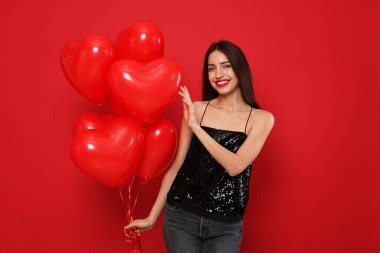 Sevgililer Günü. Kırmızı arka planda kalp şeklinde balonları olan güzel bir kadın.