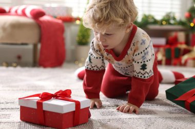 Noel hediyesi olan şirin bir bebek. Şenlikli bir odada yerde.