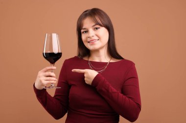 Soluk kahverengi arka planda kırmızı şarap kadehi olan profesyonel şarap garsonu.