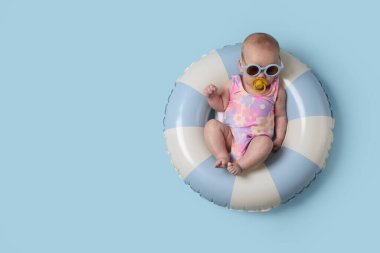 Güneş gözlüklü, emzik takan, açık mavi arka planda, şirin bir bebek. Metin için boşluk