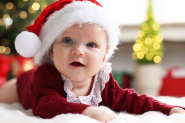 Noel Baba şapkalı şirin bebek Noel ışıklarına karşı yumuşak battaniyeli, bokeh etkisi