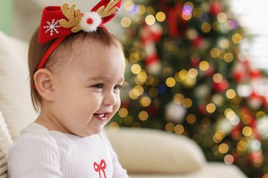 Evdeki kanepede şirin bir Noel bandı takan küçük bir bebek. Metin için boşluk