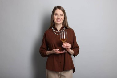 Açık gri arka planda beyaz şarap kadehi olan profesyonel şarap garsonu.