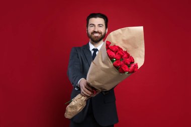 Sevgililer Günü. Kırmızı arka planda gül buketi olan bir adam.