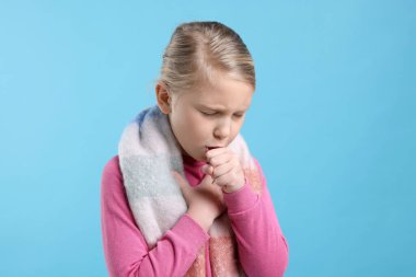 Açık mavi arka planda öksüren küçük kız. Soğuk Semptom