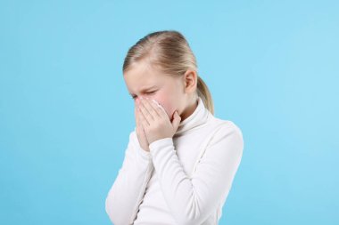 Açık mavi arka planda burnu akan küçük bir kız. Soğuk Semptom