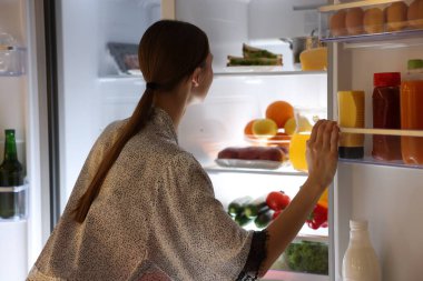 Genç kadının yanına açık buzdolabı mutfak