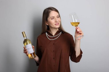 Açık gri arka planda cam ve bir şişe beyaz şarap ile profesyonel şarap garsonu.