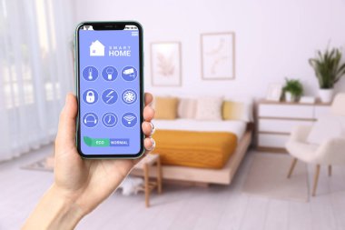 Akıllı ev sistemi. Oda özelliklerini kontrol etmek için cep telefonundaki uygulamayı kullanan adam, yakın plan