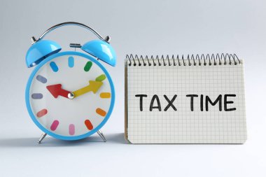 Masaya not defteriyle ve alarmlı saatle yazılmış vergi saati