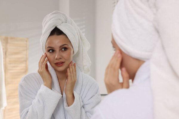 Woman with hair wrapped in towel near mirror indoors