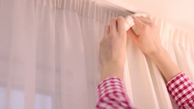 Kadın perdeleri asıyor, kapatıyor.