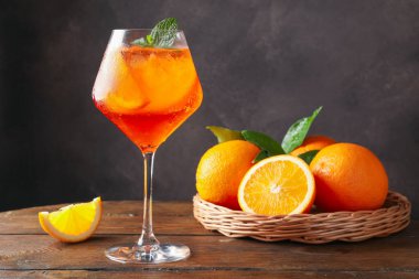 Bir bardak ferahlatıcı spritzer kokteyli. Nane ve portakallar ahşap masada.