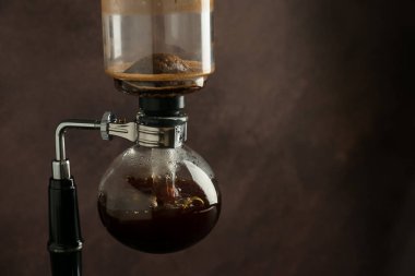 Kahverengi arka planda kahve yapan sifon (vakum) kahve makinesi, yakın plan. Metin için boşluk