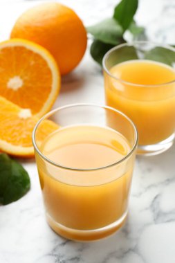 Taze portakal suyu ve beyaz mermer masada meyveler, yakın plan.