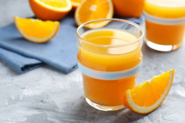 Taze portakal suyu ve meyveler gri masada, yakın plan. Metin için boşluk