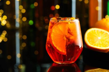 Refreshing spritzer cocktail and oranges on table in bar, closeup. Space for text