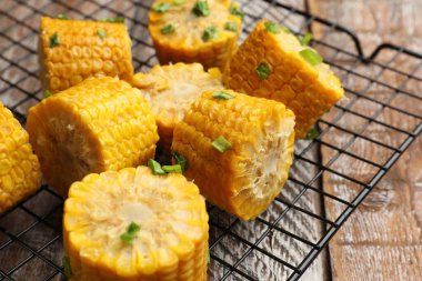 Ahşap masada yeşil soğanlı haşlanmış mısır koçanları, yakın plan.