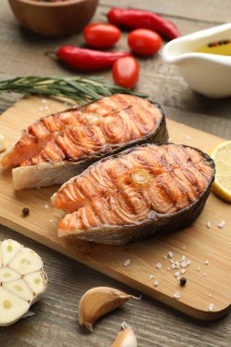 Ahşap masada servis edilen lezzetli ızgara somon biftekleri, yakın plan.