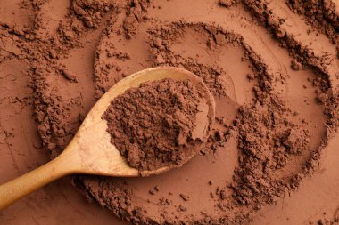 Kakao tozu ve tahta kaşık arka plan olarak, üst görünüm