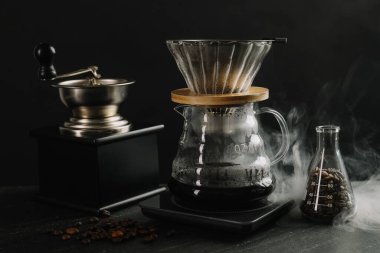 Cam kimya kahve makinesi. Lezzetli kahve, filtre, fasulye, öğütücü ve siyah masaya yakın çekim.