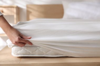 Kadın yatak çarşafını evin içine koyuyor, yakın plan.