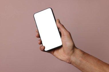 Dusty Rose arka planında boş ekranlı akıllı telefon tutan adam, yakın plan. Tasarım için model