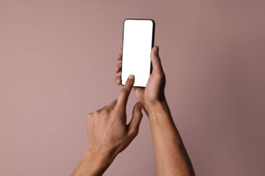 Dusty Rose arka planında boş ekranlı akıllı telefon tutan adam, yakın plan. Tasarım için model